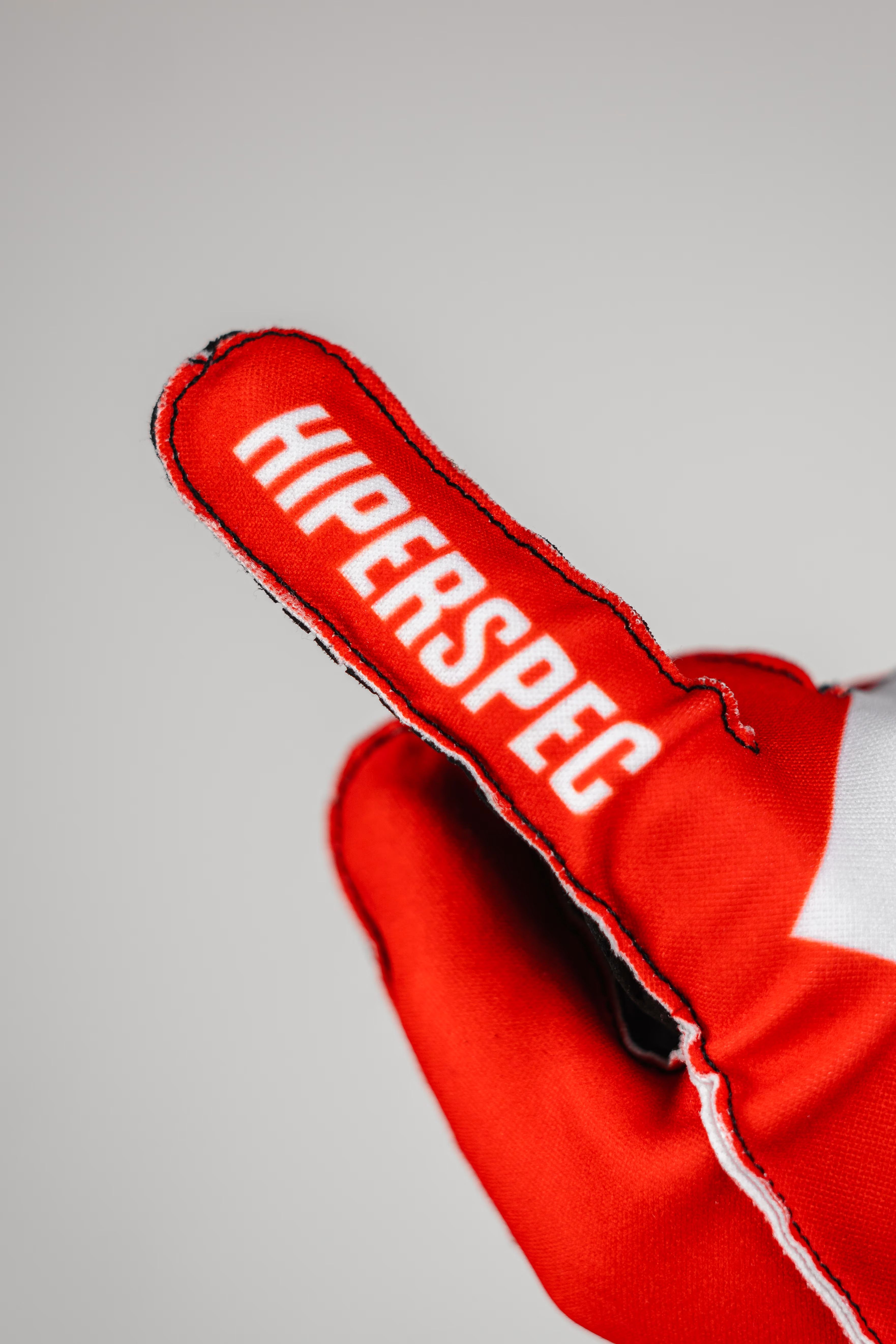 The index finger of a Crimson glove, with HIPERSPEC printed along it and the seam stitched on the outside.